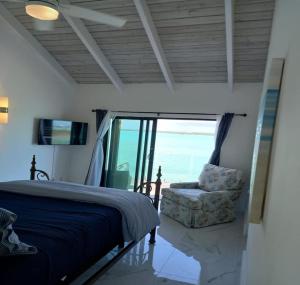 a bedroom with a bed and a chair and a window at Las Brisas Azules in Providenciales +17 photos