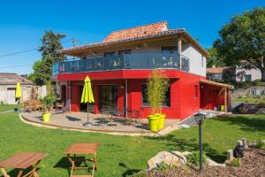 een rood huis met een terras met tafels en parasols bij Homgaïa chambres d'hôtes in Clisson