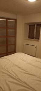 un lit blanc dans une chambre avec une fenêtre dans l'établissement Maison calme, à Payrin-Augmontel