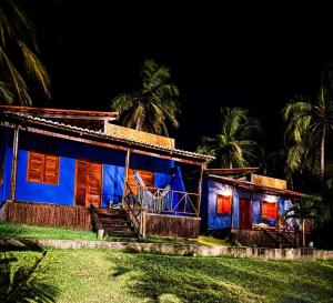 a blue house with palm trees at night at Chales Villa assu in Amontada