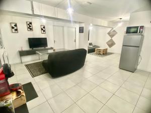 a living room with a black couch and a refrigerator at BeautifulLoft près Disneyland/Astérix/Aéroport CDG in Claye-Souilly