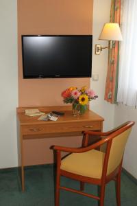 einen Schreibtisch mit einem TV an der Wand mit einem Stuhl in der Unterkunft Hotel Pension Haus Stork in Holzhausen