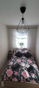 - une chambre avec un lit avec une couette à fleurs et une fenêtre dans l'établissement Apartament Słoneczny 11, à Szklarska Poręba