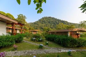 a garden in front of a building with a mountain in the background at Blue Morpho Lodge & Spa in Bajos del Toro