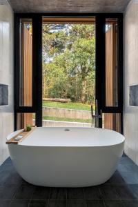 a large white bath tub in a room with a window at Casa Cave by Achei in Canela