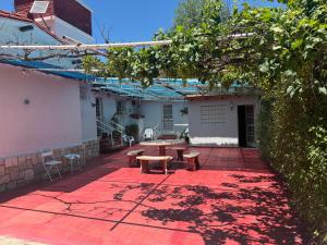a patio with a table and benches on a red rug at Nuevo complejo Clarita in Villa Carlos Paz