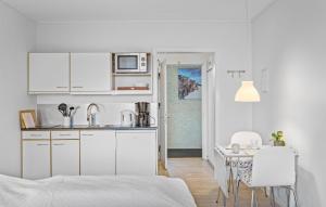 Una cocina con gabinetes blancos y una mesa y sillas. en Cozy Apartment In Gudhjem, en Gudhjem 8 fotos más