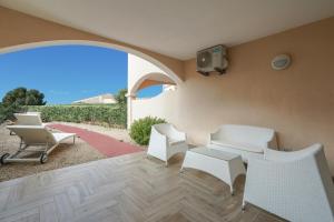 a patio with white chairs and a table and a tv at Borgo Punta Tegge il mare la spiaggia il tramonto in La Maddalena +12 photos