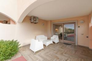a living room with two white chairs and a table at Borgo Punta Tegge il mare la spiaggia il tramonto in La Maddalena