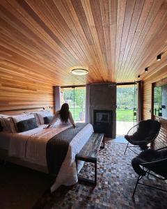 a woman is sitting on a bed in a bedroom at Vila Vicença Natural Refuge in Praia Grande