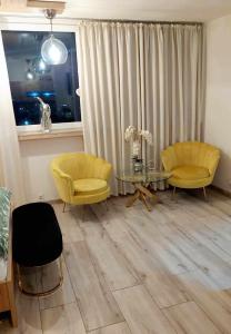 een woonkamer met gele stoelen en een glazen tafel bij Elegancki Apartament w Centrum Miasta P&P in Lubin +1 foto