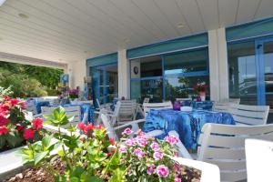 une terrasse avec des tables bleues, des chaises blanches et des fleurs dans l'établissement Hotel Rosalba, à Riccione
