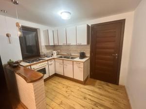 a kitchen with white cabinets and a wooden floor at Casa Ilenucăi in Bîrsana