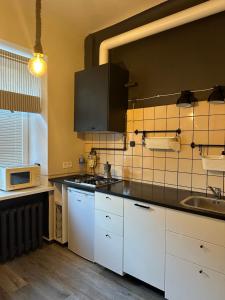a kitchen with white cabinets and a sink and a microwave at Cozy Apartment- Self Check- In in Riga