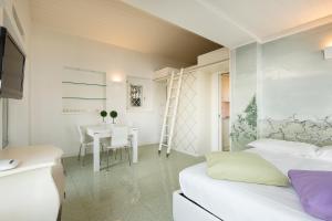 a bedroom with two beds and a table and a desk at Maison du Lac in Stresa