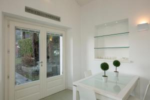 a white dining room with a white table and chairs at Maison du Lac in Stresa