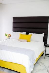 a large bed with a black headboard and yellow pillows at Eden Groove Luxury self catering Guesthouse in Matsulu