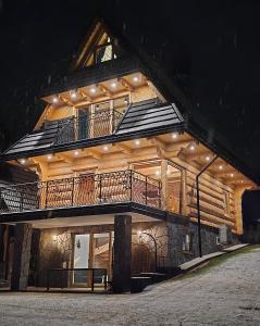 een gebouw met een balkon met verlichting bij Topory Prestige House sauna & jacuzzi in Zakopane