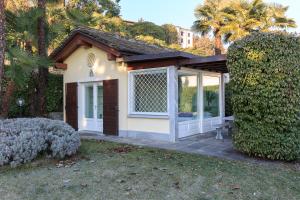 a small house with a large window and bushes at Maison du Lac in Stresa