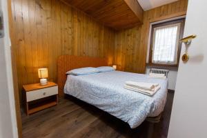 Un dormitorio con una cama y una mesita de noche con una lámpara. en MaR Maturi Appartamenti con due bagni ideali per 6 e 10 persone nel centro di Campiglio, en Madonna di Campiglio