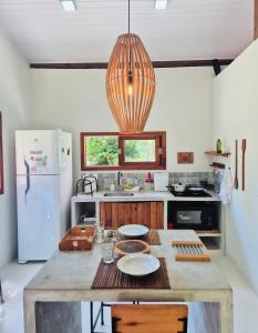a kitchen with a table and a pendant light at Casa Raiz 1 Moreré - A 3min da praia in Moreré