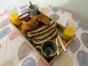 a tray of bread and croissants on a table with orange juice at Vue Cité Médiévale Castel View in Carcassonne +37 photos