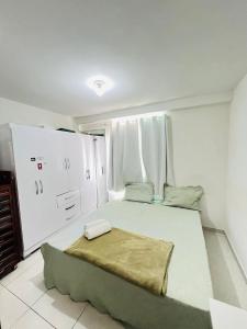 - une chambre avec un grand lit blanc et une couverture dans l'établissement Suíte Areia dos Anjos, à Arraial do Cabo