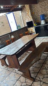 a wooden picnic table sitting on top of a stone floor at Piscina, Churrasqueira, Ar Condicionado e 3 Vagas de Garagem in Mongaguá