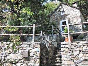 una vecchia casa in pietra con cancello e recinzione di Rustico Gatto by Fewotessin a Cugnasco