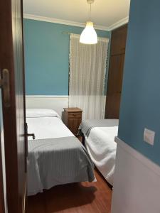 a bedroom with two beds and a blue wall at Apartamentos Gerena 5A derecha in Gerena