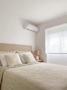 a white bedroom with a bed and a window at Apartamento de un dormitorio en Edificio "Luna de Mar" in Punta del Este