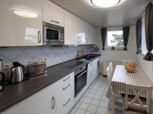 a kitchen with white cabinets and a table in it at Huus Jan in Spiekeroog