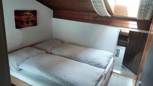 a small room with a bed with white sheets at Apartment Birkenstrasse 54 Engelberg in Engelberg