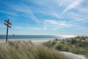 a beach with a sign in the sand and the ocean at Drifthuus 1 klein in Spiekeroog +20 photos