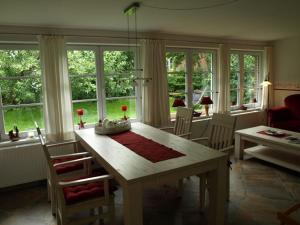 a living room with a table and chairs and windows at Pastors Tuun in Spiekeroog
