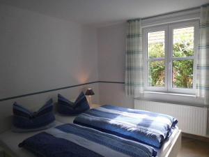 a bedroom with a bed with blue and white pillows at Pastors Tuun in Spiekeroog
