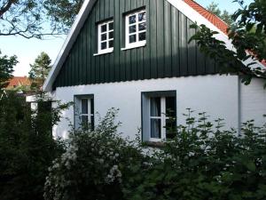 a green and white house with two windows at Pastors Tuun in Spiekeroog