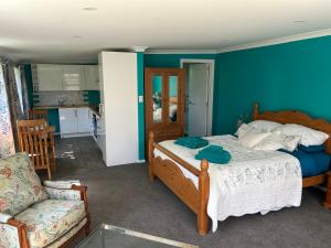 a bedroom with a bed and a couch and a chair at Beachy Sounds Studio in Carters Beach