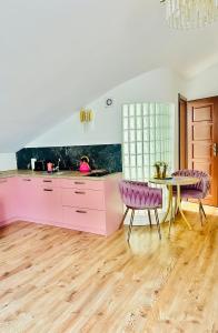 een roze keuken met een tafel en paarse stoelen bij Apartament Premium Cichowo in Cichowo