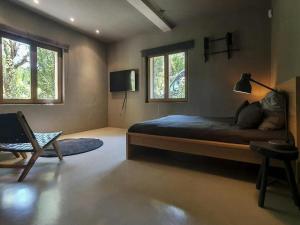 a bedroom with a bed and a chair and two windows at Holiday home with wooden-beamed patio in Santa Gertrudis de Fruitera