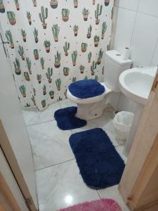 La salle de bains est pourvue de toilettes et de 2 tapis bleus. dans l'établissement Casa de praia verde mar, à Itanhaém