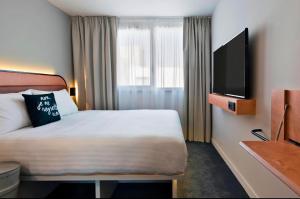 a hotel room with a bed and a flat screen tv at Pavillon Tawfik 1 à 4 personnes chez l’habitant in Bagneux