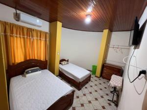 a small room with two beds and a tv at La Casa Verde in Iquitos