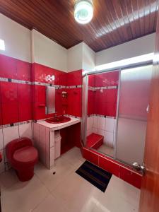 a red bathroom with a toilet and a shower at La Casa Verde in Iquitos