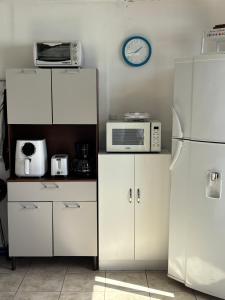 a kitchen with white cabinets and a clock on the wall at Atardecer D Oro, Casa de playa in Esparza