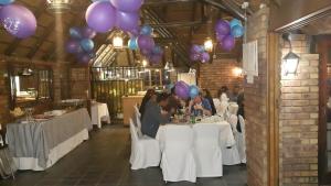 a group of people sitting at tables with purple balloons at Albatross B&B in Benoni
