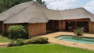 a building with a thatched roof and a swimming pool at Albatross B&B in Benoni