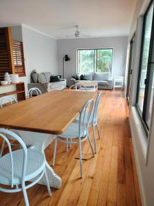 a dining room and living room with a wooden table and chairs at Private Bush & Beach Retreat in Eudlo