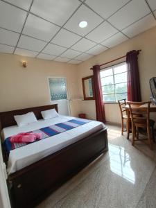 a bedroom with a bed and a table and chairs at The Golden Bow in Seeduwa