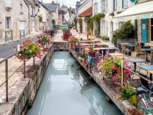 a canal in a city with tables and flowers at Maison cosy proche Loire avec climatisation - FR-1-590-531 in Beaugency